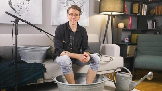 Dr. Johannes Wimmer sitzt auf einem Sofa. © Screenshot 