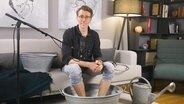 Dr. Johannes Wimmer sitzt auf einem Sofa. © Screenshot 