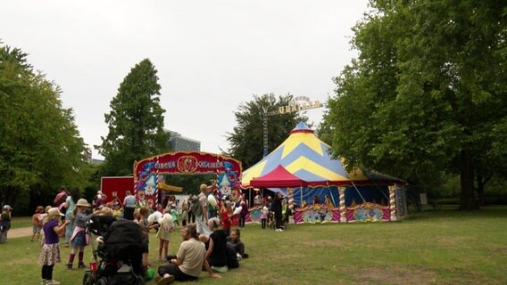 Zirkuszelt auf einer Wiese mit Besuchern davor. © Screenshot 