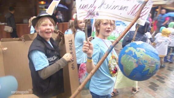 Kinder demonstrieren für mehr Vielfalt und Toleranz auf der Welt. Mit dabei haben sie eine selbst gebastelte Erde. © Screenshot 