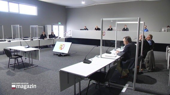 Beteiligte eines Gerichtsverfahrens sitzen in einem Gerichtssaal. © Screenshot 