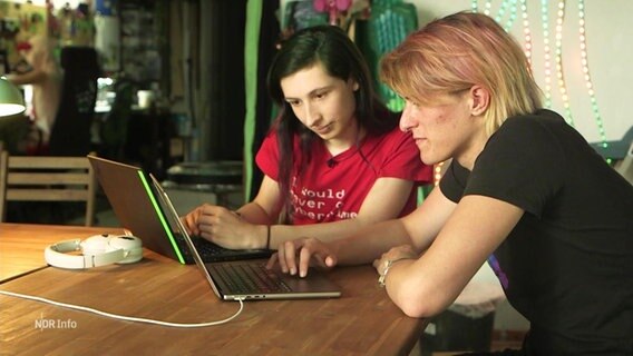 Zwei Personen schauen auf einen Laptop. © Screenshot 