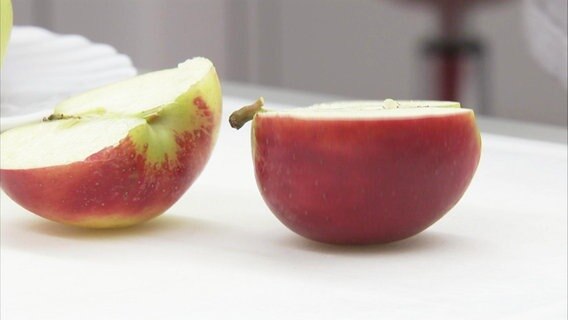 Ein aufgeschnittener Apfel liegt auf einem Tisch. © Screenshot 