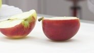 Ein aufgeschnittener Apfel liegt auf einem Tisch. © Screenshot 