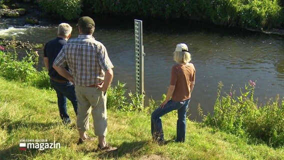 Drei Menschen stehen am niedrigen Pegelstand eines Flusses. © Screenshot 