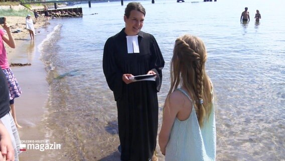 Eine evangelische Pfarrerin tauft ein Mädchen in der Ostsee. © Screenshot 