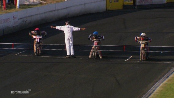 Auf einer Speedway-Strecke warten Motocross-Fahrer auf das Signal des Schiedsrichters. © Screenshot 