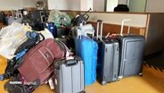 Mehrere Koffer auf einem Haufen vor einem Flughafenschalter. © Screenshot 