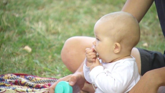 Ein Baby sitzt auf einer Wiese. © Screenshot 