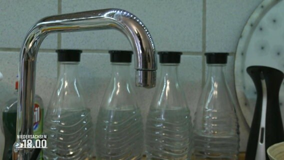 Vier Wasserflaschen vor einem Wasserhahn. © Screenshot 