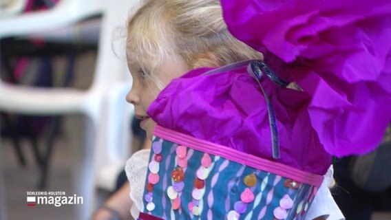 Ein kleines Mädchen hält eine Schultüte im Arm. © Screenshot 