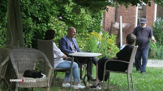 Menschen sitzen zusammen im Garten an einem Tisch. © Screenshot 
