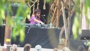 Auf dem MS Dockville Festival mixt eine DJane auf einer Bühne für ihr tanzendes Publikum. © Screenshot 