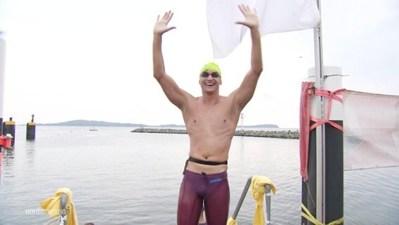 Ein Schwimmer streckt nach seinem Sieg bei einem Wettkampf die Arme freudig in die Luft. © Screenshot 