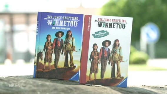 Auf einem Untergrund stehen zwei neuere Ausgaben des Kinderbuchklassikers "Winnetou". © Screenshot 