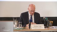 Christian Pegel, Innenminister Mecklenburg-Vorpommerns, liest bei einer Pressekonferenz eine Mitteilung vor. © Screenshot 