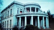 Eine prunkvolle, weiße Villa am Hamburger Elbufer dient als Kulisse für eine Szene im Film "Der amerikanische Freund". © Screenshot 