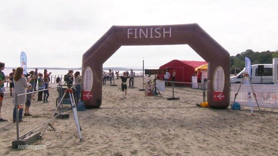 Bei einem Triathlon kommt ein Teilnehmer als Erster im Ziel an. © Screenshot 