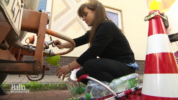 Eine Frau füllt sich an einem Trinkwassertank etwas ab. © Screenshot 