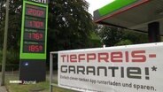 An einer Tankstelle hängt ein Banner mit Aufschrift "Tiefpreis-Garantie" © Screenshot 