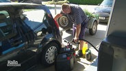 Ein Mann füllt sich an einer Zapfsäule Treibstoff in einen Kanister ab. © Screenshot 
