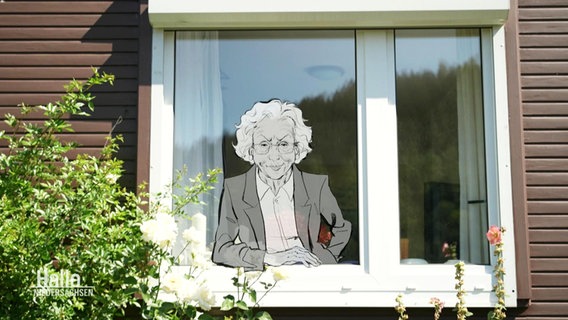 In einem Fenster eines Hauses ist eine Schwarz-Weiß-Illustration einer älteren, ernst guckenden Dame zu sehen. © Screenshot 