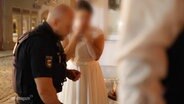 Polizeibeamte stehen rund um eine weinende Frau in einem Hochzeitskleid. © Screenshot 