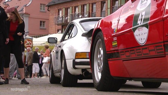 Zwei ältere Porsche auf einem Straßenfest. © Screenshot 