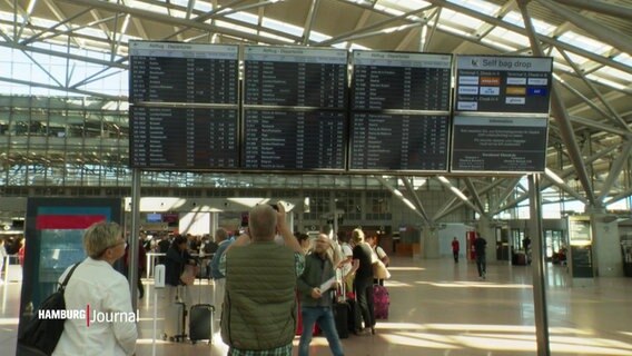 Reisende betrachten eine Infotafel eines Flughafens. © Screenshot 