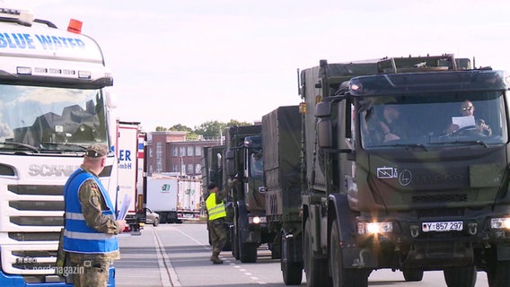 Mehrere Militärtrucks rollen in einer Kolonne an LKWs vorbei. © Screenshot 
