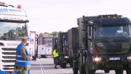 Mehrere Militärtrucks rollen in einer Kolonne an LKWs vorbei. © Screenshot 