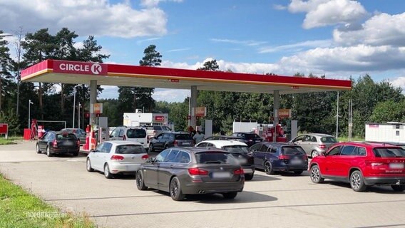 Mehrere Autos stehen Schlange an den Zapfsäulen einer Tankstelle. © Screenshot 