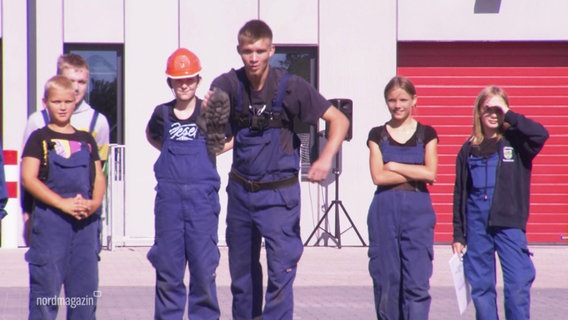 Mehrere Kinder in Arbeitsausrüstung schauen einem Jungen zu, der mit einem Stiefel zum Wurf ausholt. © Screenshot 