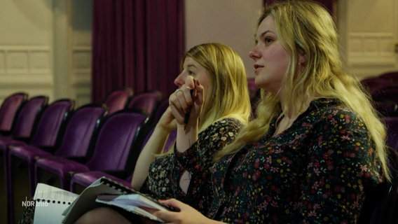 Zwei Frauen sitzen während einer Theaterprobe im Publikum. © Screenshot 