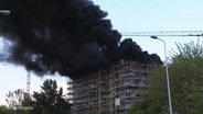 Bei einem Großbrand an einer Baustelle in Rostock steigen schwarze Wolken auf © Screenshot 