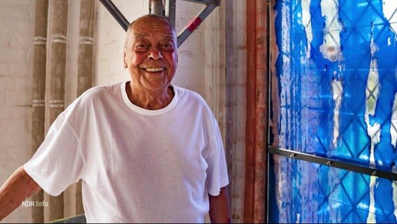 Der Künstler Günther Uecker neben einem von ihm entworfenen blauen Fenster im Schweriner Dom. © Screenshot 