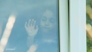 Ein Mädchen steht hinter einem geschlossenem Fenster © Screenshot 