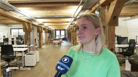 Eine junge Frau im Interview in einem Großraumbüro. © Screenshot 