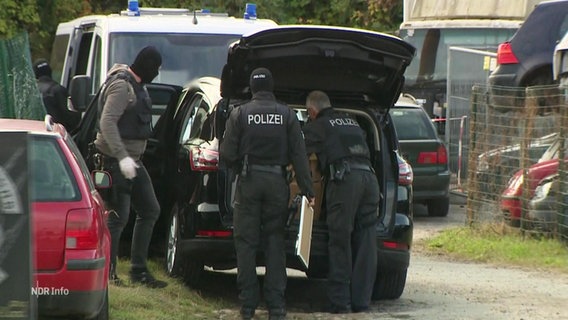 Polizeibeamte stehen am offenen Kofferaum eines Autos © Screenshot 