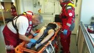 Sanitätspersonal bei einer Seenotrettungsübung versorgen eine Person auf einer Trage im Innenraum eines Schiffs. © Screenshot 
