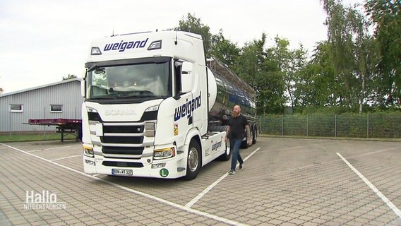 Ein weißer LKW parkt auf einem Autohof, daneben geht ein Mann in schwarzem T-Shirt. © Screenshot 