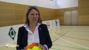 Die schleswig-holsteinische Justiz- und Gesundheitsministerin Kerstin von der Decken hält einen Fußball in der Hand und steht in einer Sporthalle. © Screenshot 