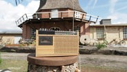 Ein altes Radio steht vor einer alten Mühle. © Screenshot 