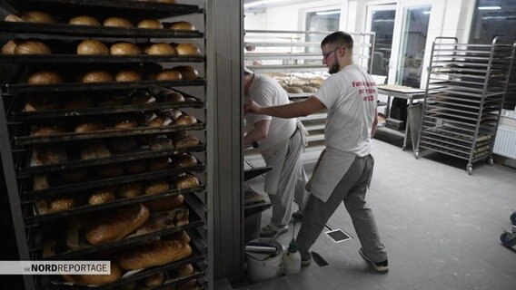 Bäcker mit frisch gebackenen Broten in einer Bäckerei. © Screenshot 