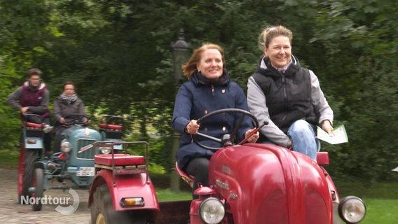Zwei Frauen fahren mit einem Oldimer-Trecker. © Screenshot 