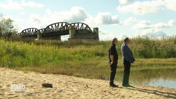 Zwei Männer vor der zerstörten Brücke. © Screenshot 