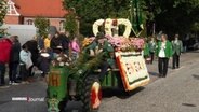 Ein mit Blumen geschmückter Festwagen auf einem Erntedankfestzug © Screenshot 
