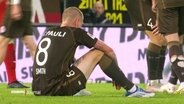 Ein Spieler des FC St. Pauli sitzt auf einem Fußballplatz © Screenshot 