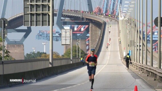 Ein Läufer auf der Köhlbrandbrücke, im Hintergrund die Brücke und andere Laufende. © Screenshot 