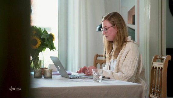 Eine Frau sitzt an einem Tisch an einem Laptop. © Screenshot 